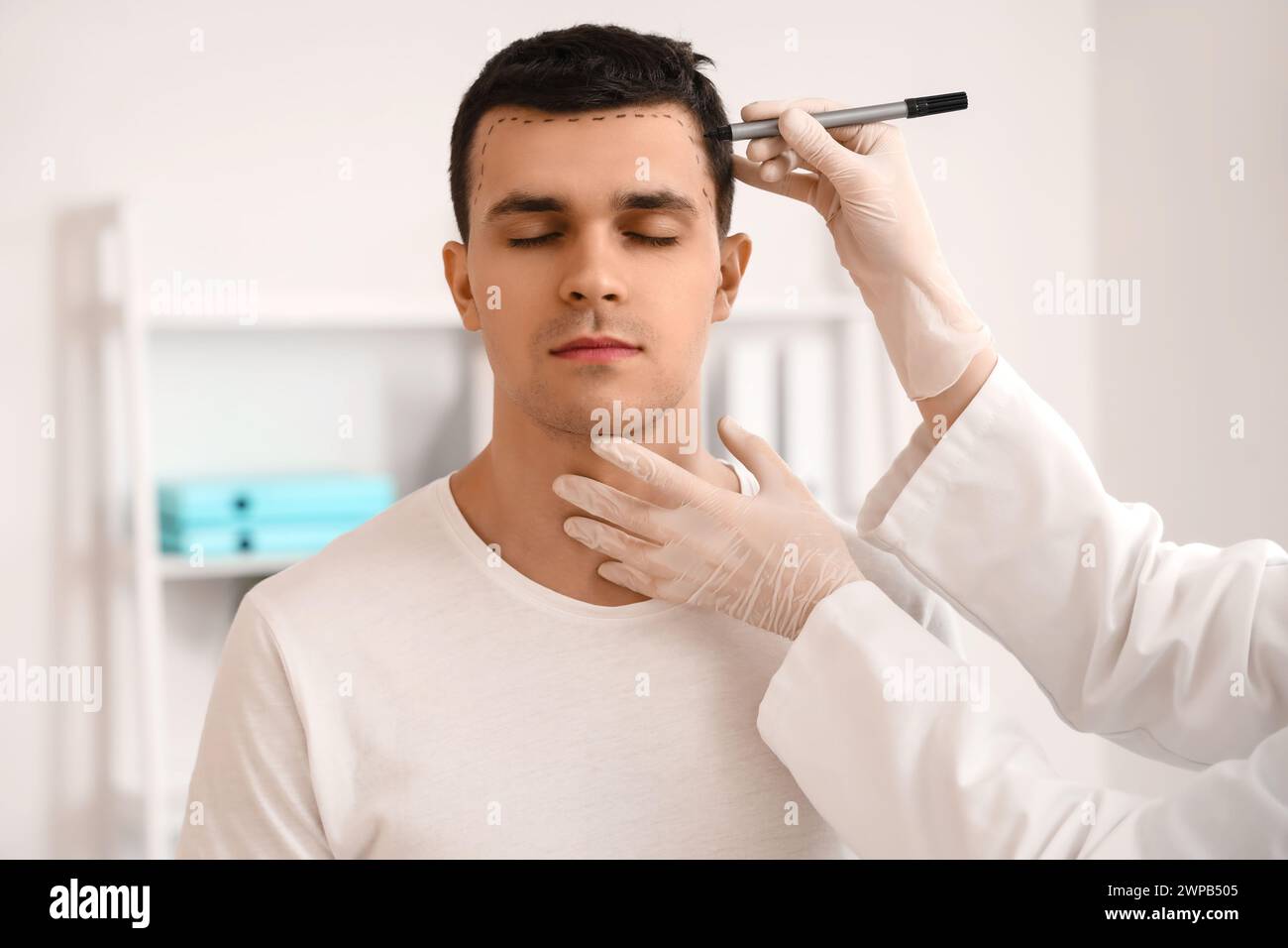 Docteur marquant la tête du jeune homme avec un problème de perte de cheveux en clinique, gros plan Banque D'Images