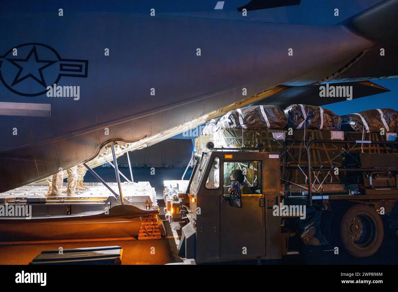 Azraq, Jordanie. 05 mars 2024. Des soldats de l'armée américaine et des aviateurs de l'armée de l'air chargent des palettes d'aide humanitaire dans la soute d'un avion C-130J Super Hercules de l'armée de l'air américaine à la base aérienne de Muwaffaq Salti, le 5 mars 2024 à Azraq, gouvernorat de Zarqa, Jordanie. L’aide alimentaire sera larguée par voie aérienne aux réfugiés palestiniens pris au piège de la guerre israélienne contre le Hamas. Crédit : SRA Lauren Jacoby/US Airforce photo/Alamy Live News Banque D'Images