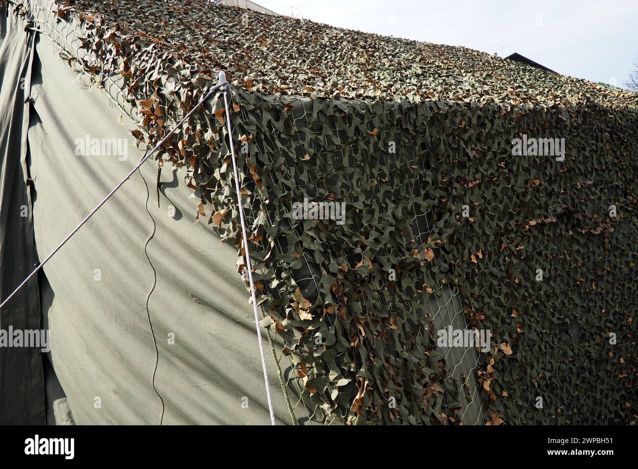 Un filet vert camouflage est drapé sur une tente de champ. Camp militaire. Installation d'une tente à l'extérieur. Survie touristique. Complexe mobile de terrain pour temporaire Banque D'Images