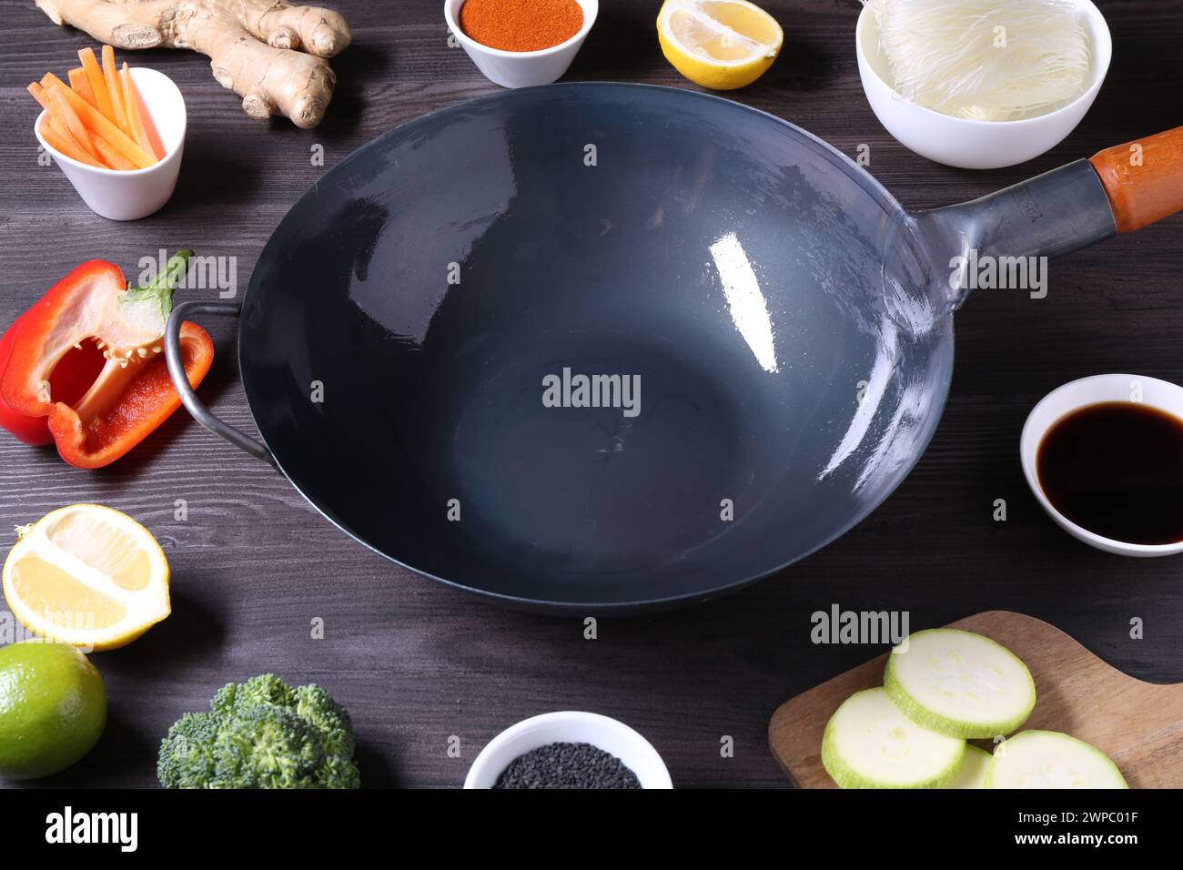 Wok en fer vide entouré d'ingrédients sur une table en bois gris foncé Banque D'Images