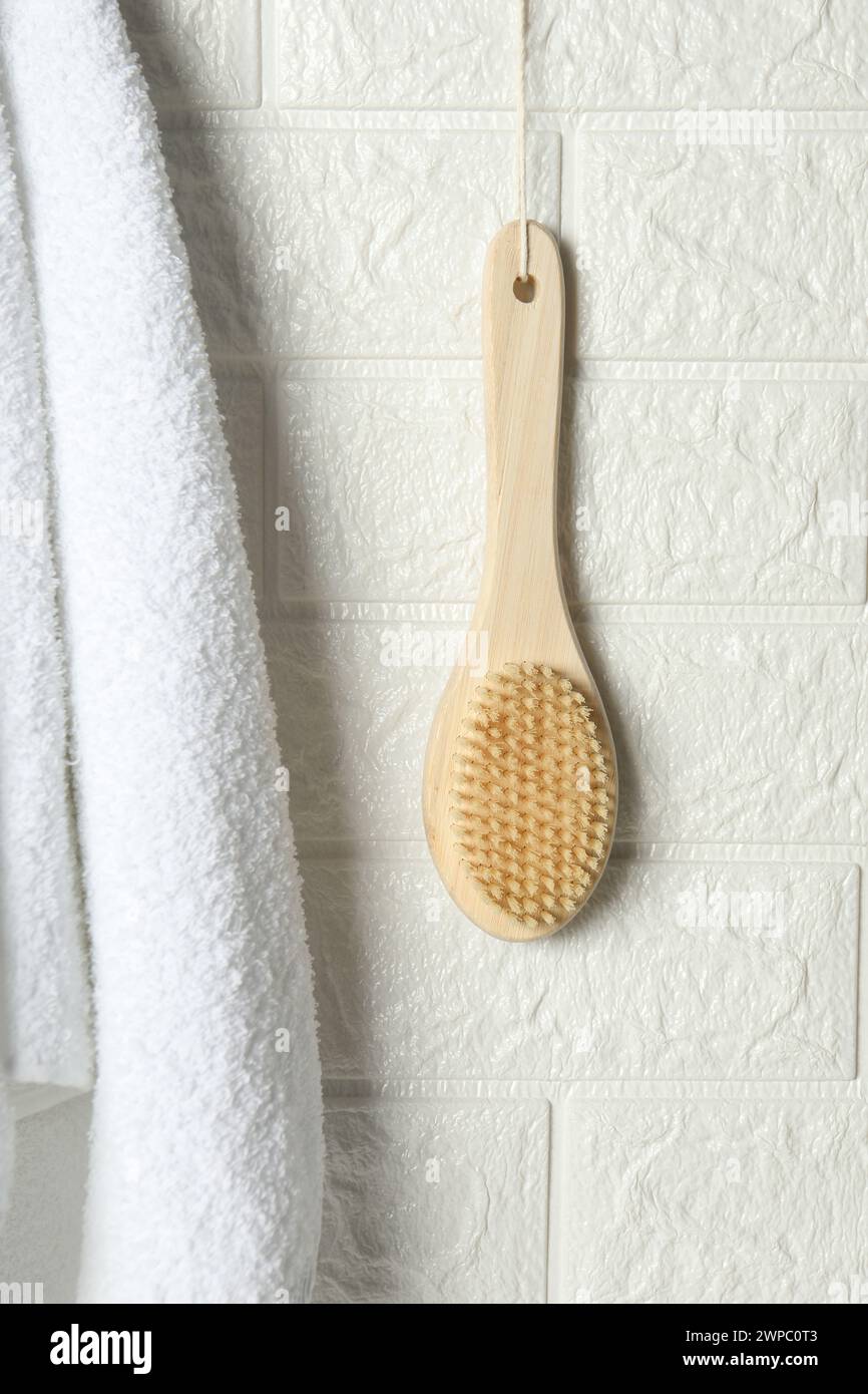 Accessoires de bain. Brosse en bambou et serviette éponge sur le mur de briques blanches Banque D'Images