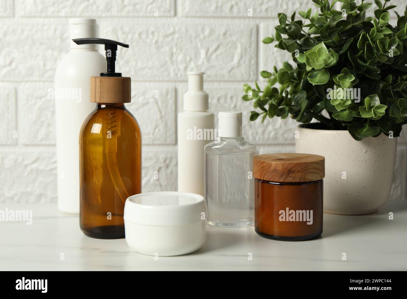 Accessoires de bain. Produits de soins personnels sur la table blanche près du mur de briques Banque D'Images