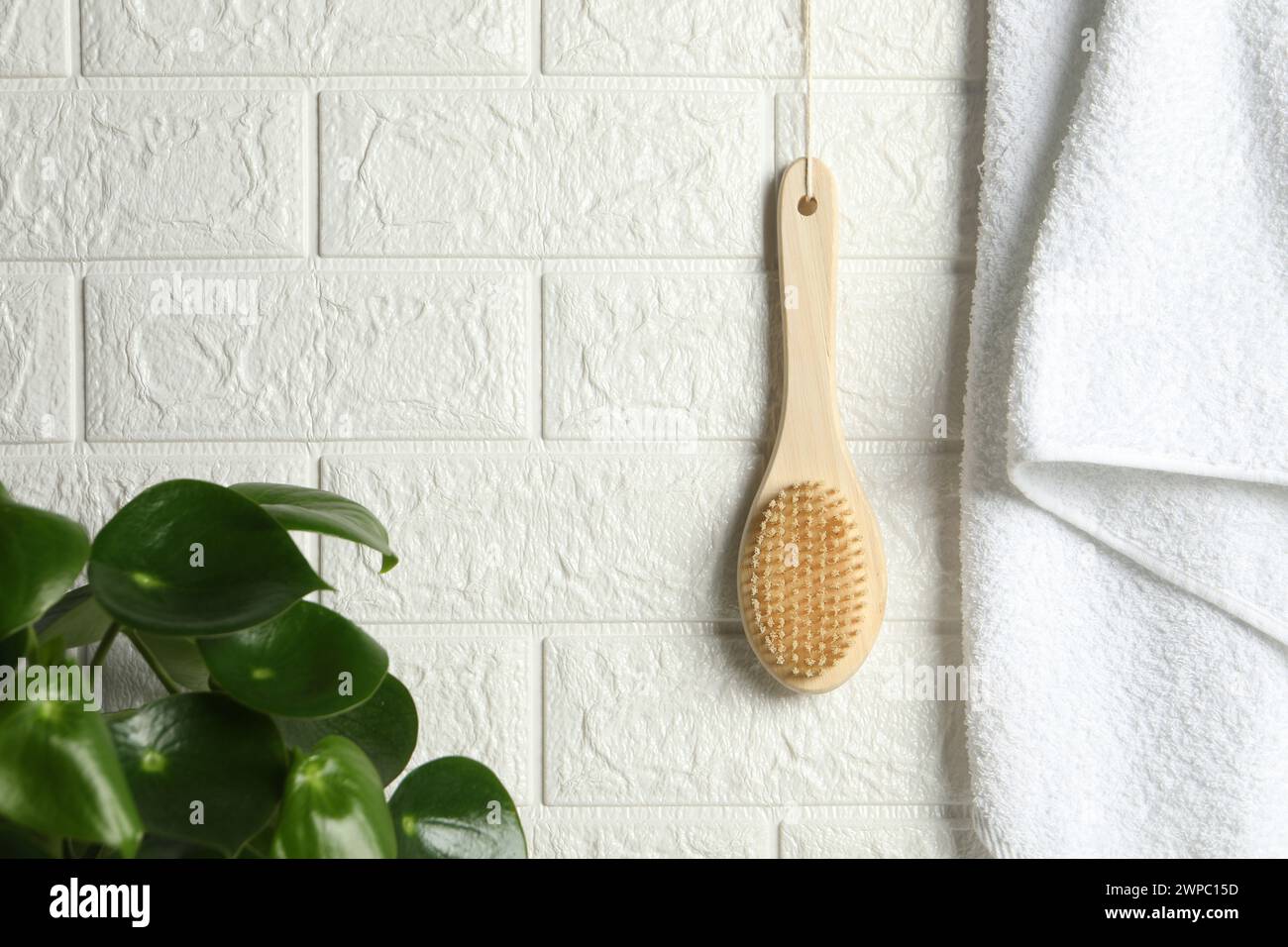 Accessoires de bain. Brosse en bambou et serviette éponge sur le mur de briques blanches Banque D'Images