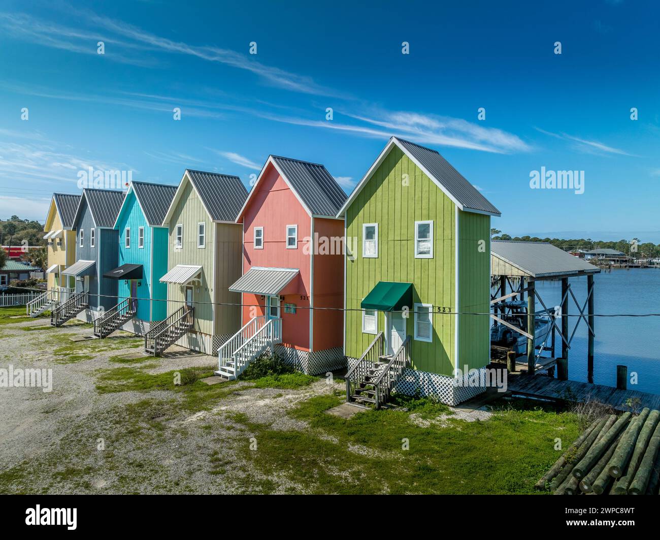 Maisons de vacances colorées de deux étages avec jaune vif, bleu, vert, peinture rose, marches en bois à la porte, structure de stationnement de bateau à l'arrière sur l'île de Dauphin A Banque D'Images