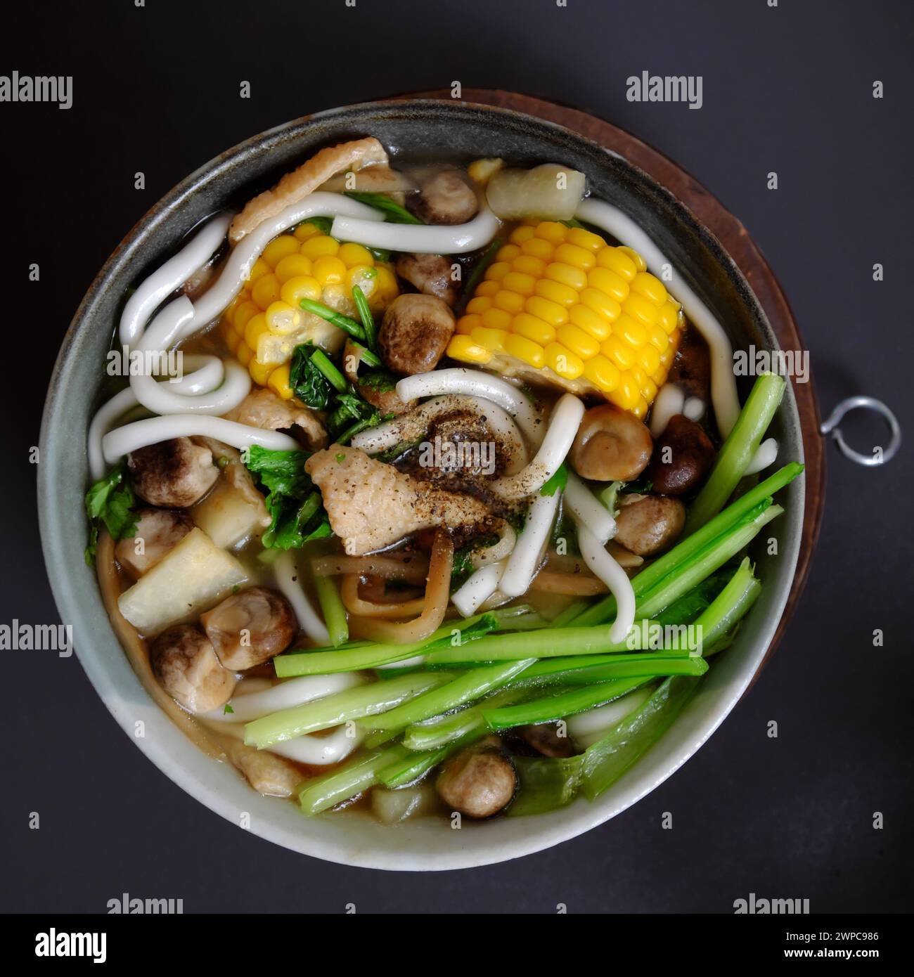 Soupe de nouilles de riz végétal avec garniture de légumes comme maïs jaune, tofu, champignons, délicieux bol végétalien prêt à manger sur gris Banque D'Images