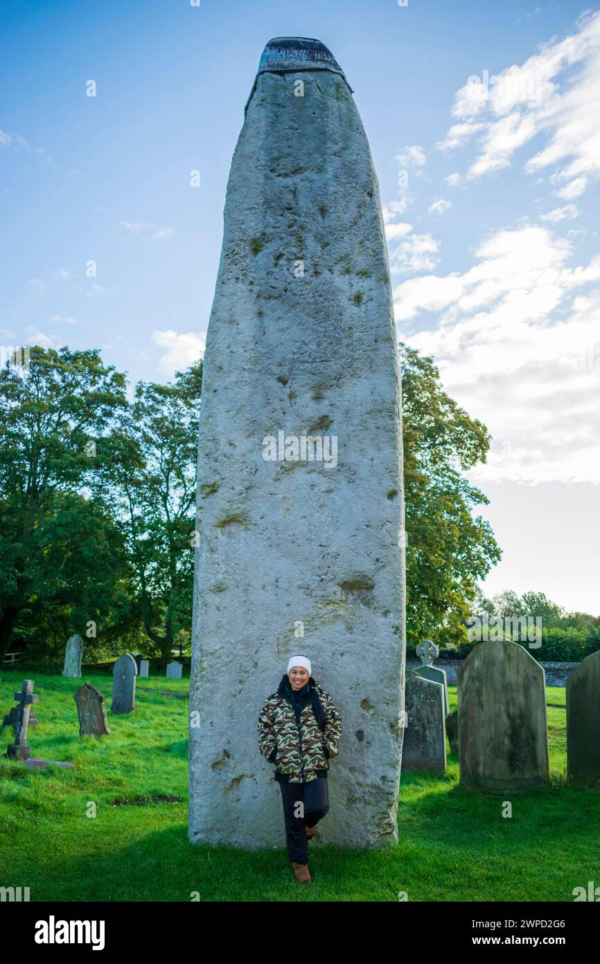 Une femme posant à la pierre préhistorique la plus élevée d'Angleterre, Rudston Monolith Banque D'Images