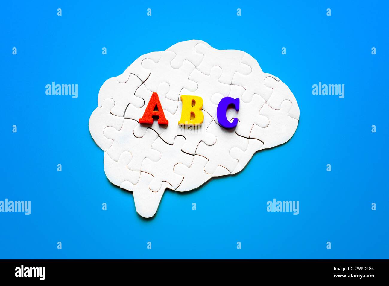 Puzzle en forme de cerveau orné de lettres en bois colorées décrivant l'ABC, sur fond bleu tranquille. Apprentissage des langues étrangères Concepp Banque D'Images