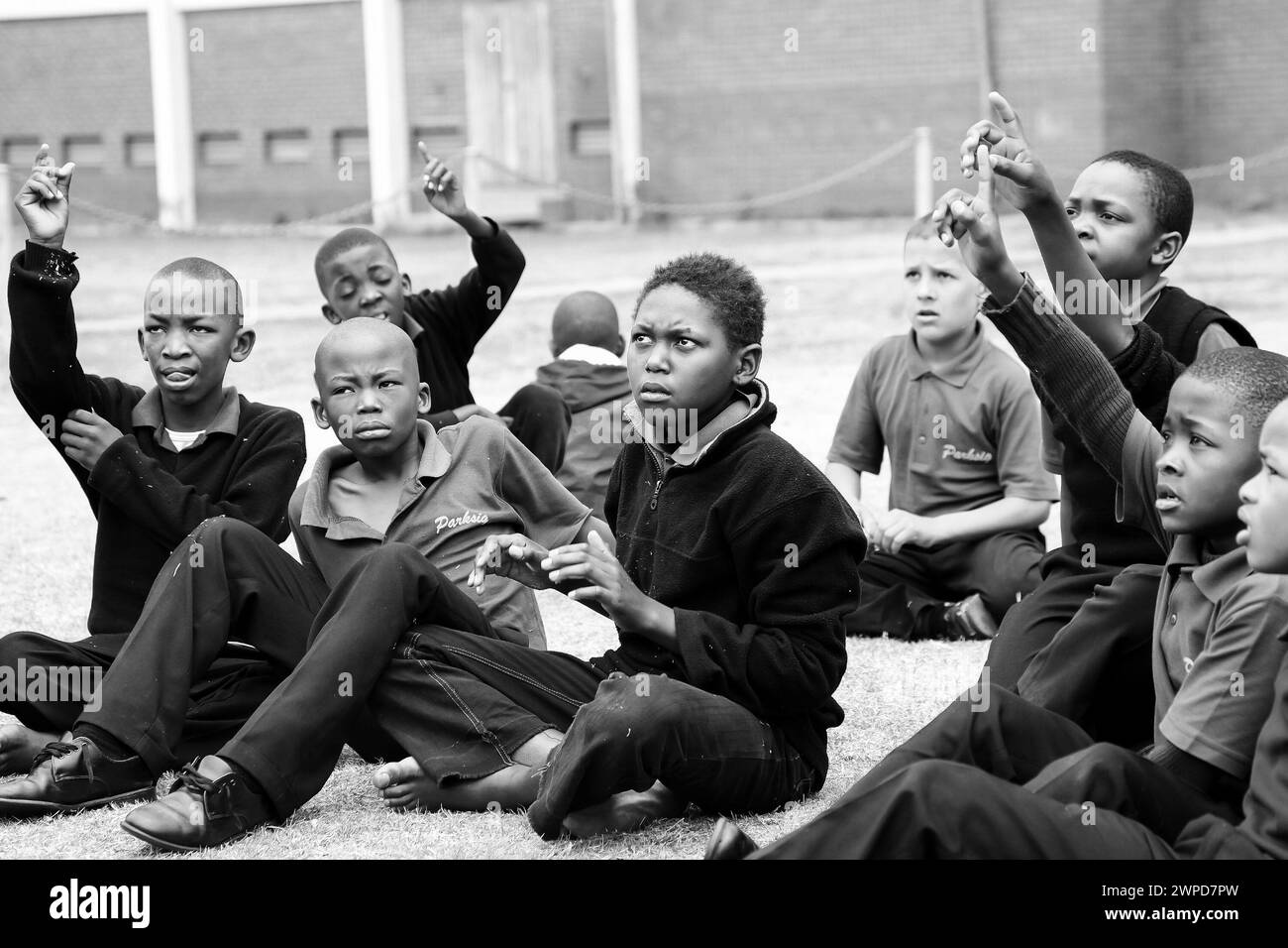 Un groupe diversifié d'enfants assis sur le sol, à Johannesburg, en Afrique du Sud, en niveaux de gris Banque D'Images