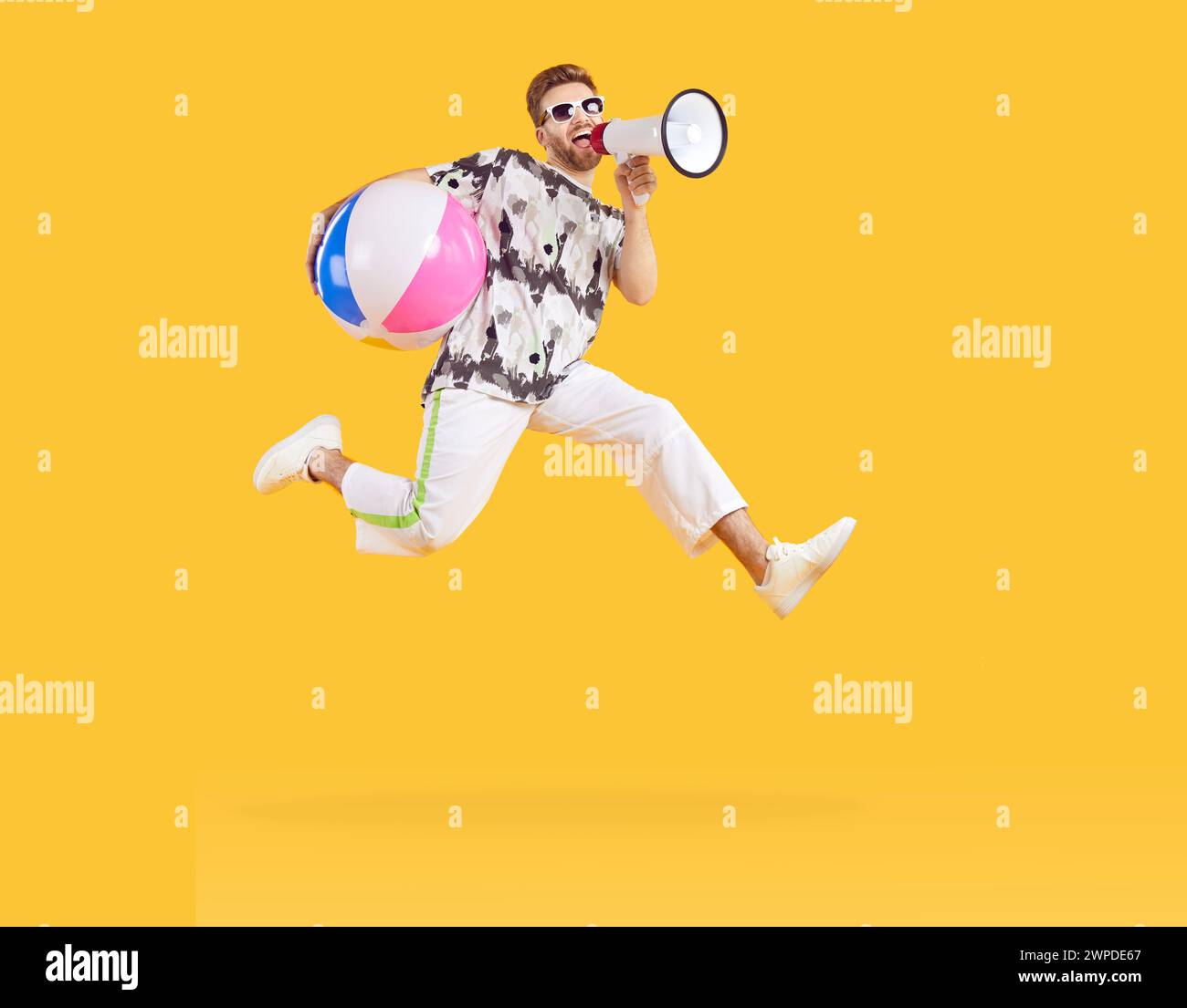 Homme excité sautant avec boule de mer gonflable et criant dans le mégaphone Banque D'Images