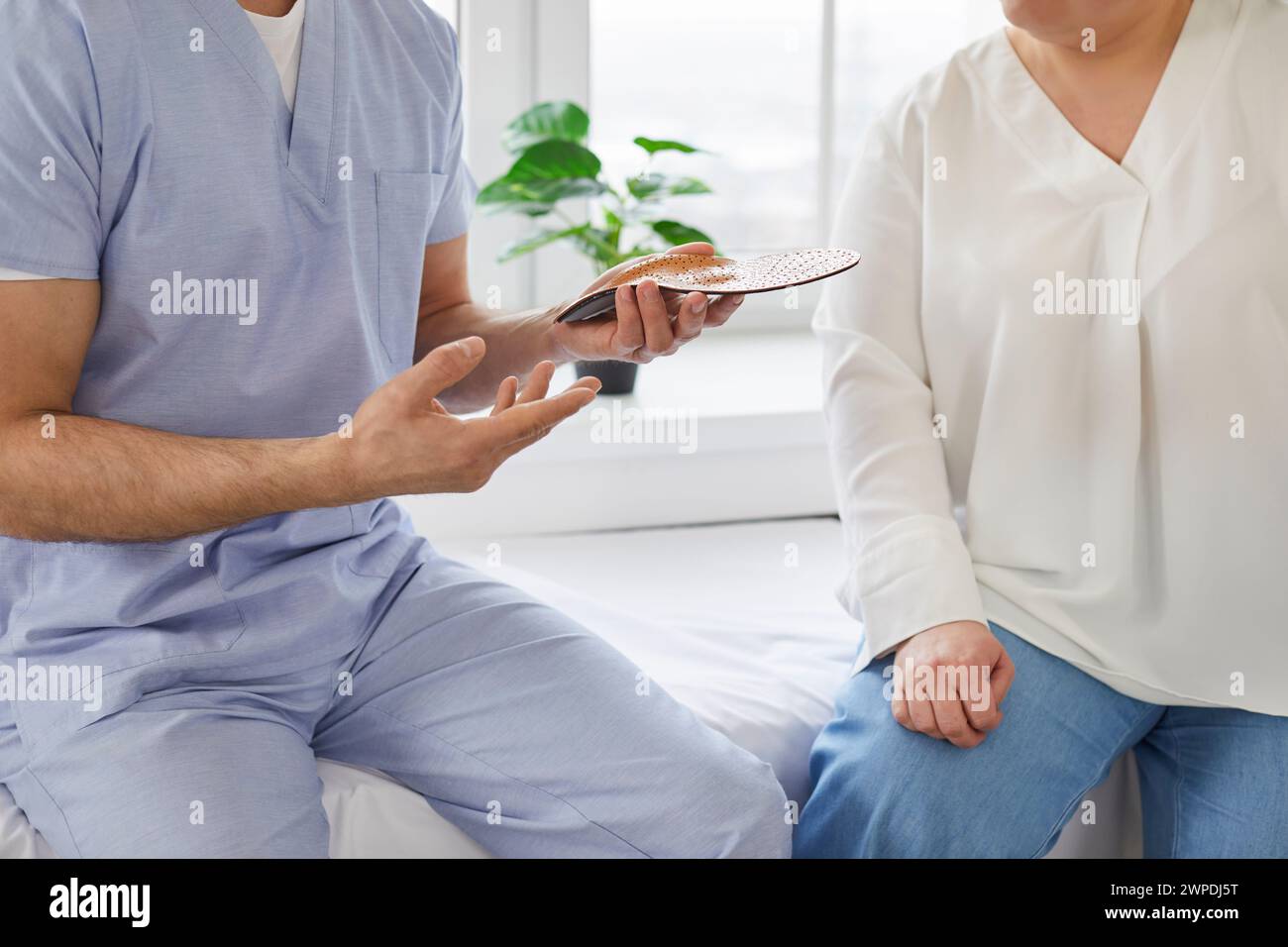 Le médecin conseille le patient sur les semelles orthopédiques individuelles pour la correction des pieds plats. Banque D'Images