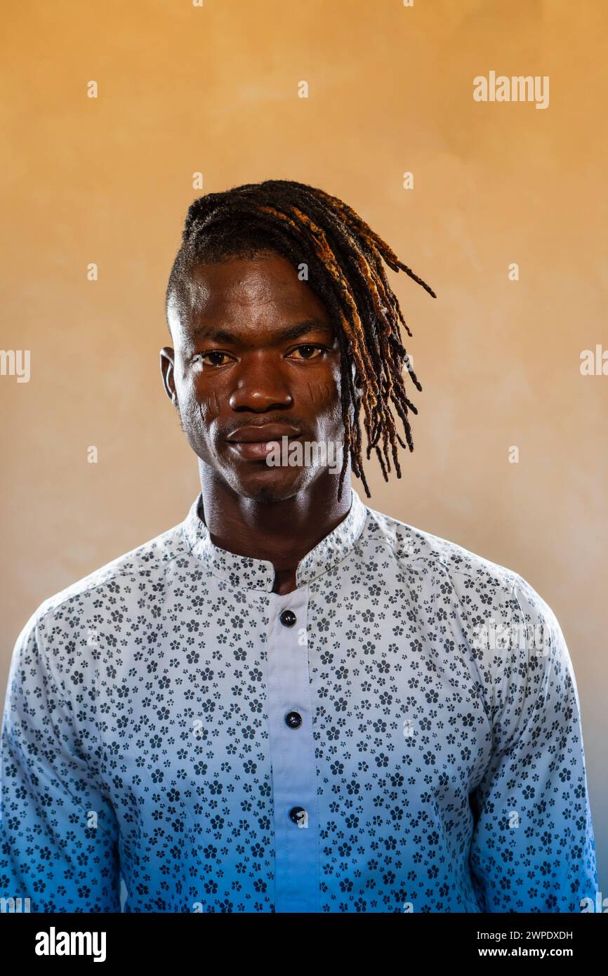 Portrait studio d'un homme africain confiant avec des dreadlocks élégants portant une chemise à motifs floraux, exsudant l'élégance et l'identité culturelle Banque D'Images