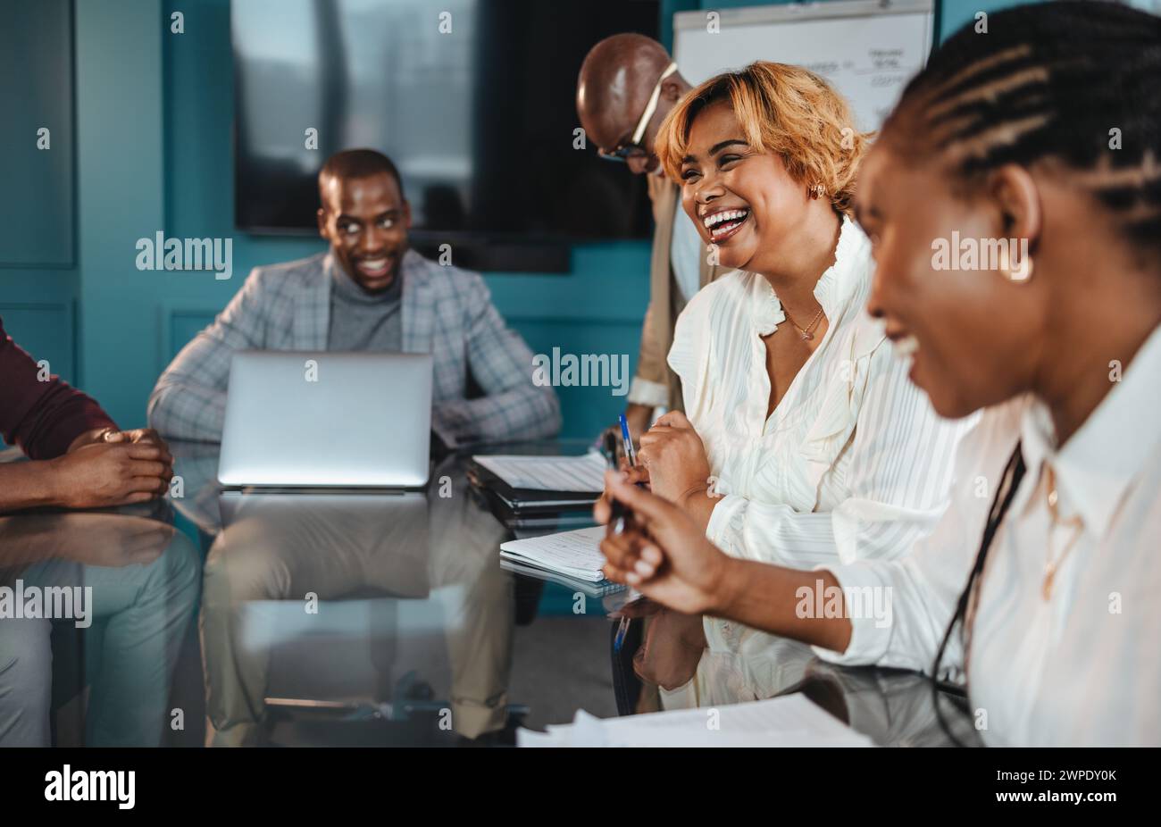 Groupe de professionnels dans un bureau ont une réunion d'affaires réussie. Ils discutent, rient et affichent une atmosphère de travail d'équipe heureuse dans la salle de réunion. Banque D'Images