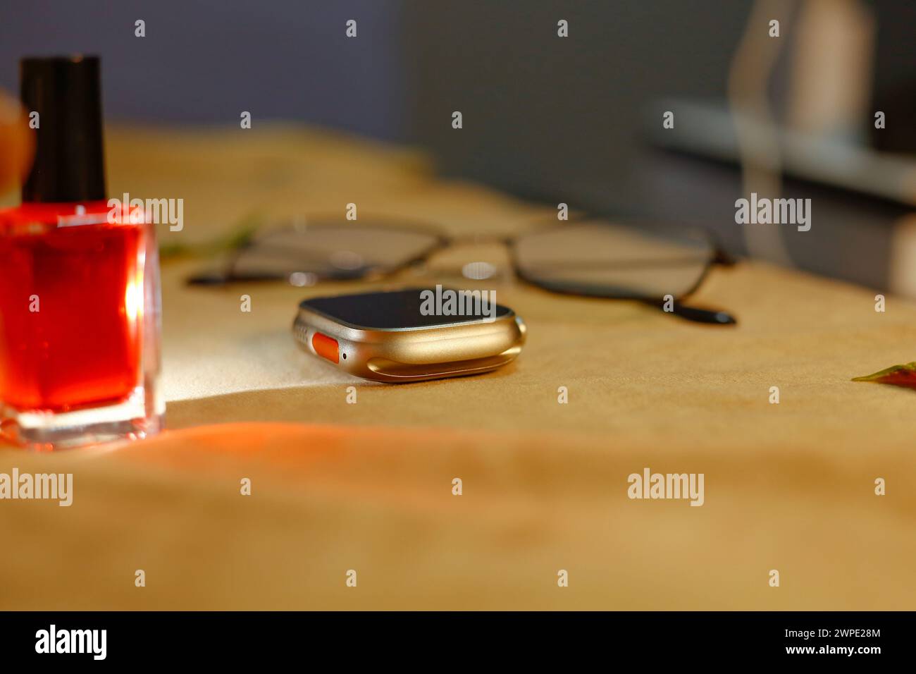 Ladite vue de montre intelligente élégante, vernis à ongles et verre de soleil. Dans le tableau fond marron. Réflexion de la lumière Banque D'Images