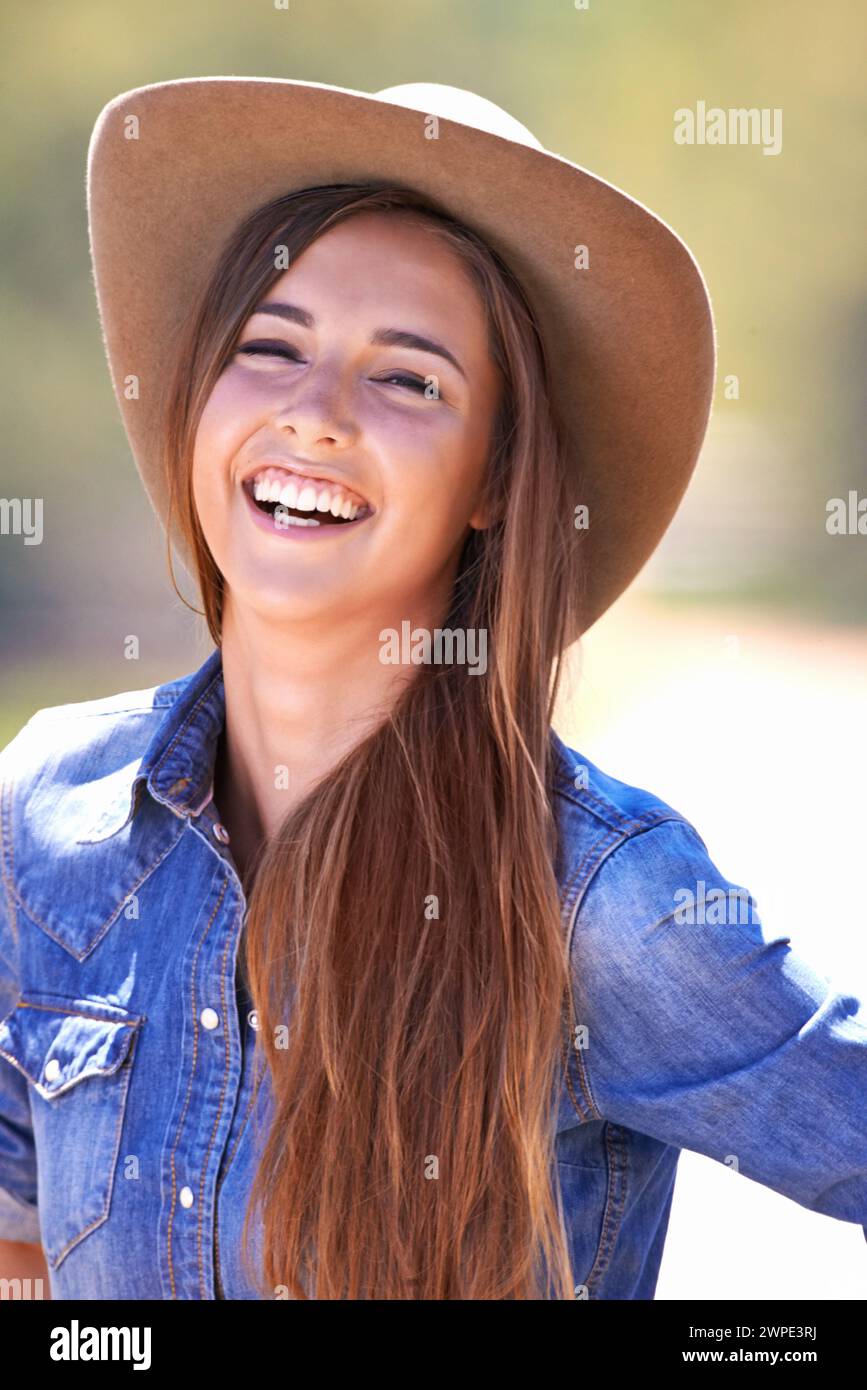 Portrait, mode et sourire de cowgirl à la ferme ou au ranch pour l'agriculture ou la durabilité en été. Campagne, texas ou ouest avec jeunes heureux Banque D'Images