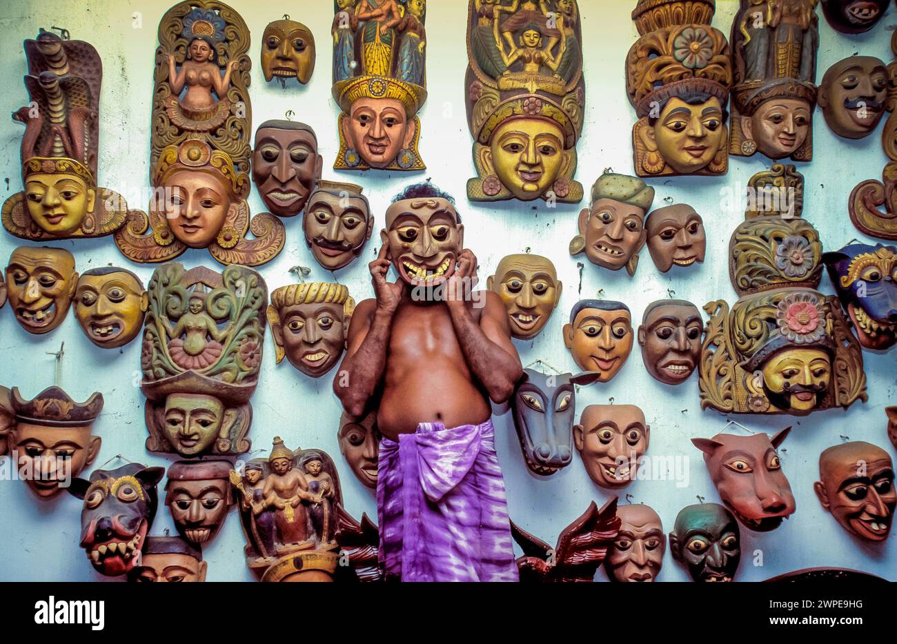 Sri Lanka, Ambalangode, un vendeur dans un magasin montre les masques en bois traditionnellement sculptés qu'il vend. Banque D'Images