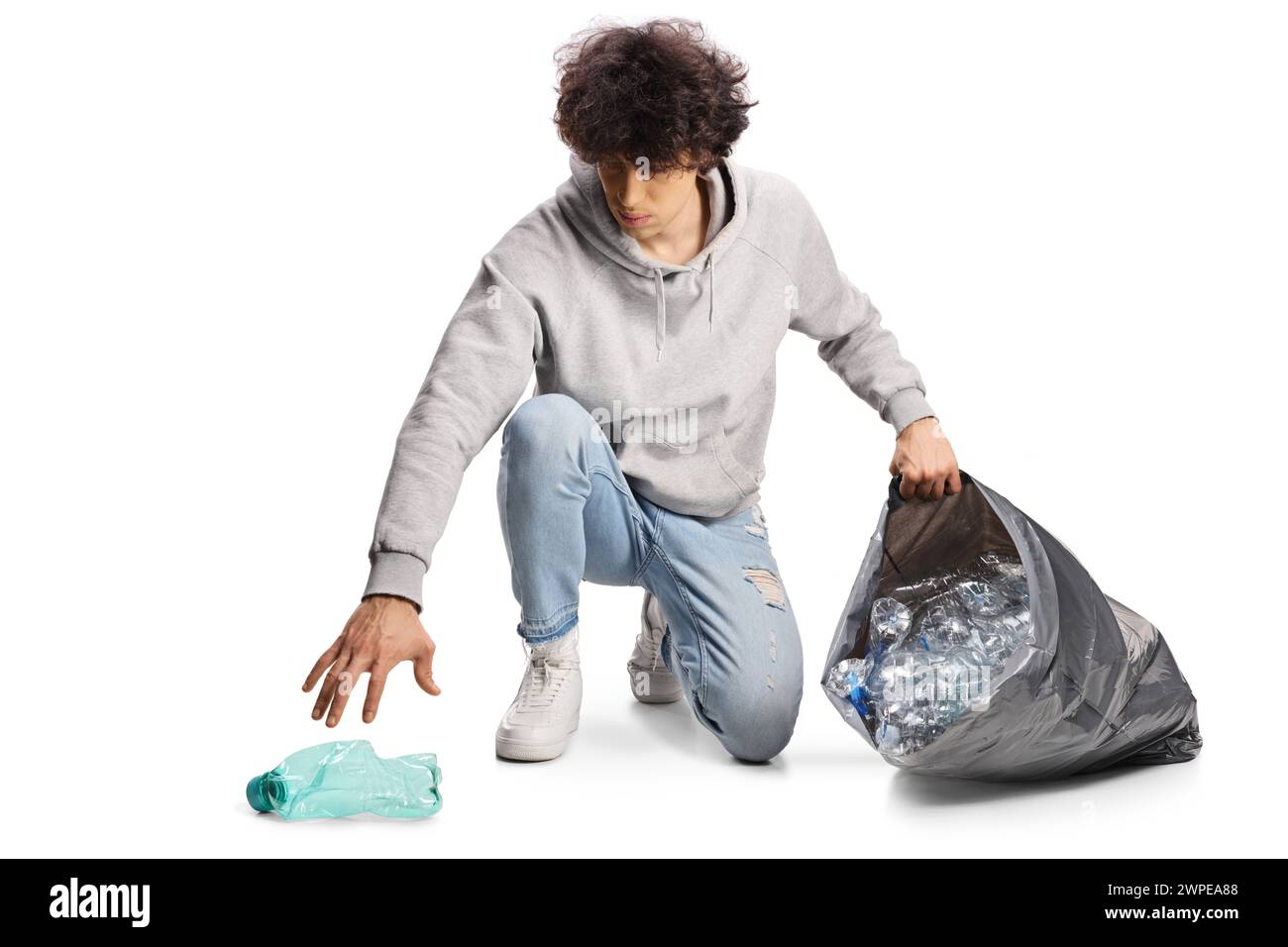 Guy collectant des bouteilles en plastique dans un sac à déchets noir isolé sur fond blanc Banque D'Images