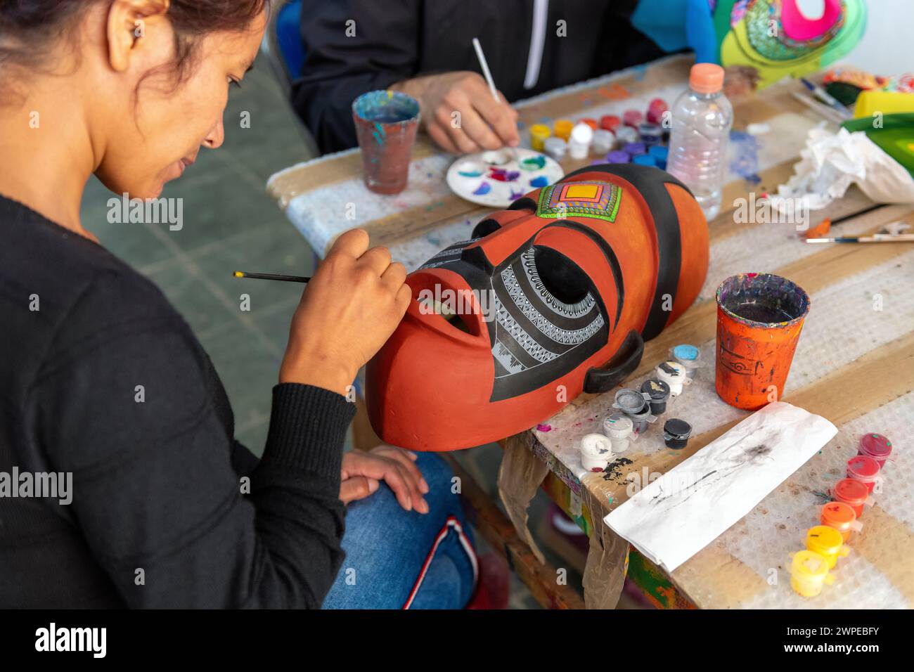Jeune femme artisanale peignant un masque mexicain en bois de copal fait à la main, arts et artisanat dans le style alebrije, San Martin Tilcajete, vallée d'Oaxaca, Mexique. Banque D'Images