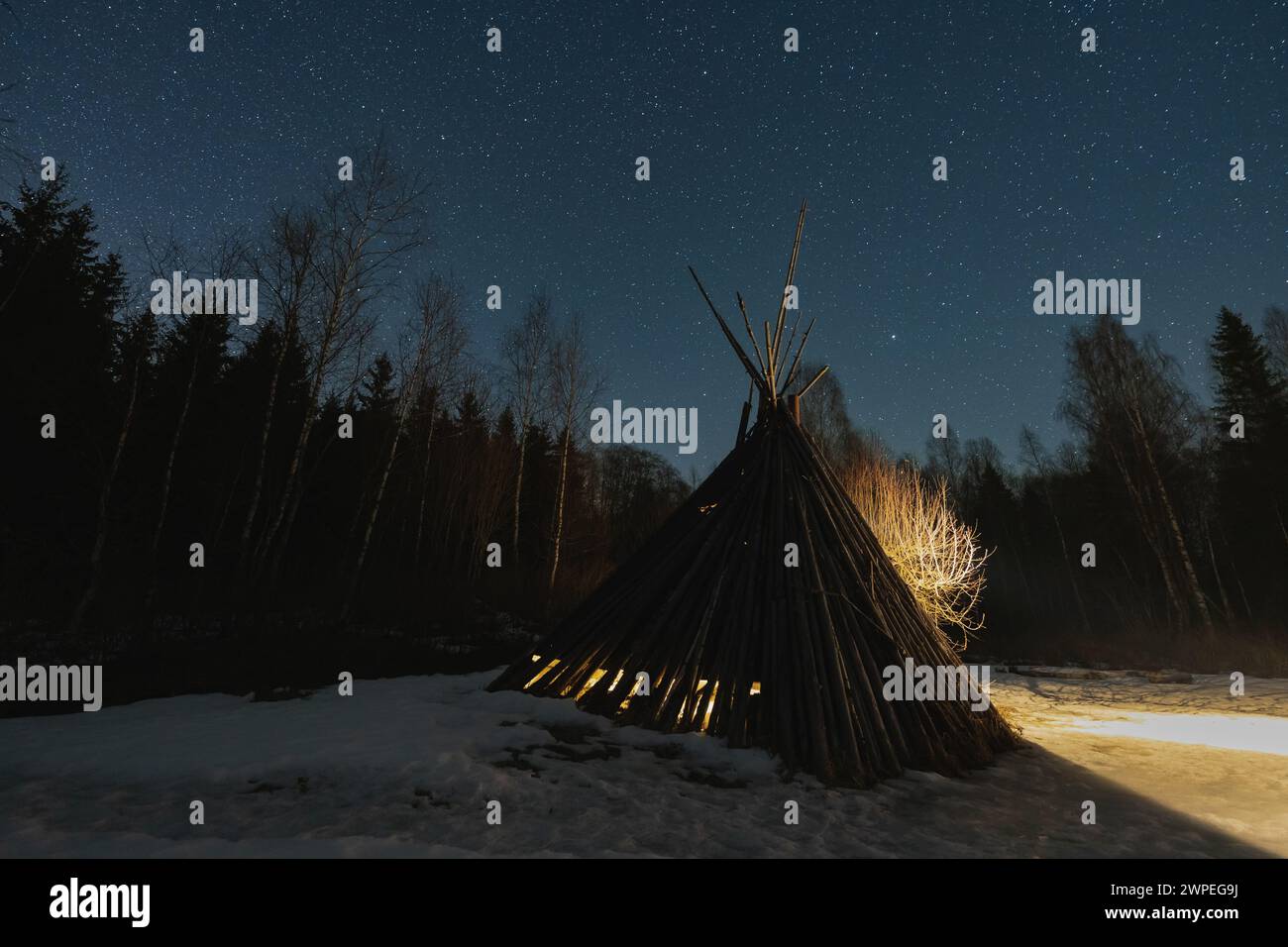 Photo de nuit dans la nature, une cabane dans la forêt d'où vient la lumière, ciel étoilé. Banque D'Images