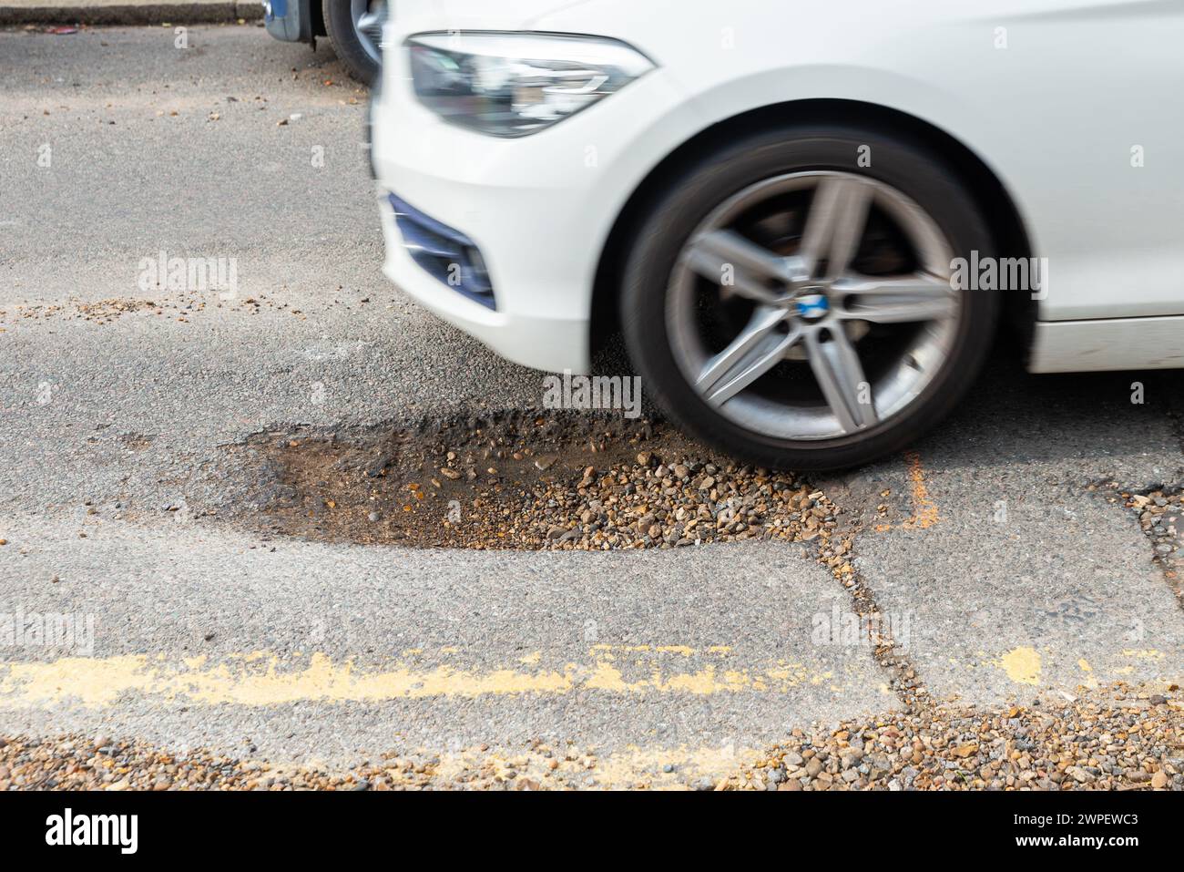 Grand nid de poule dans une route à Westcliff on Sea, Essex, Royaume-Uni, en besoin de réparation. Voiture sur le point de conduire dans le pot Banque D'Images