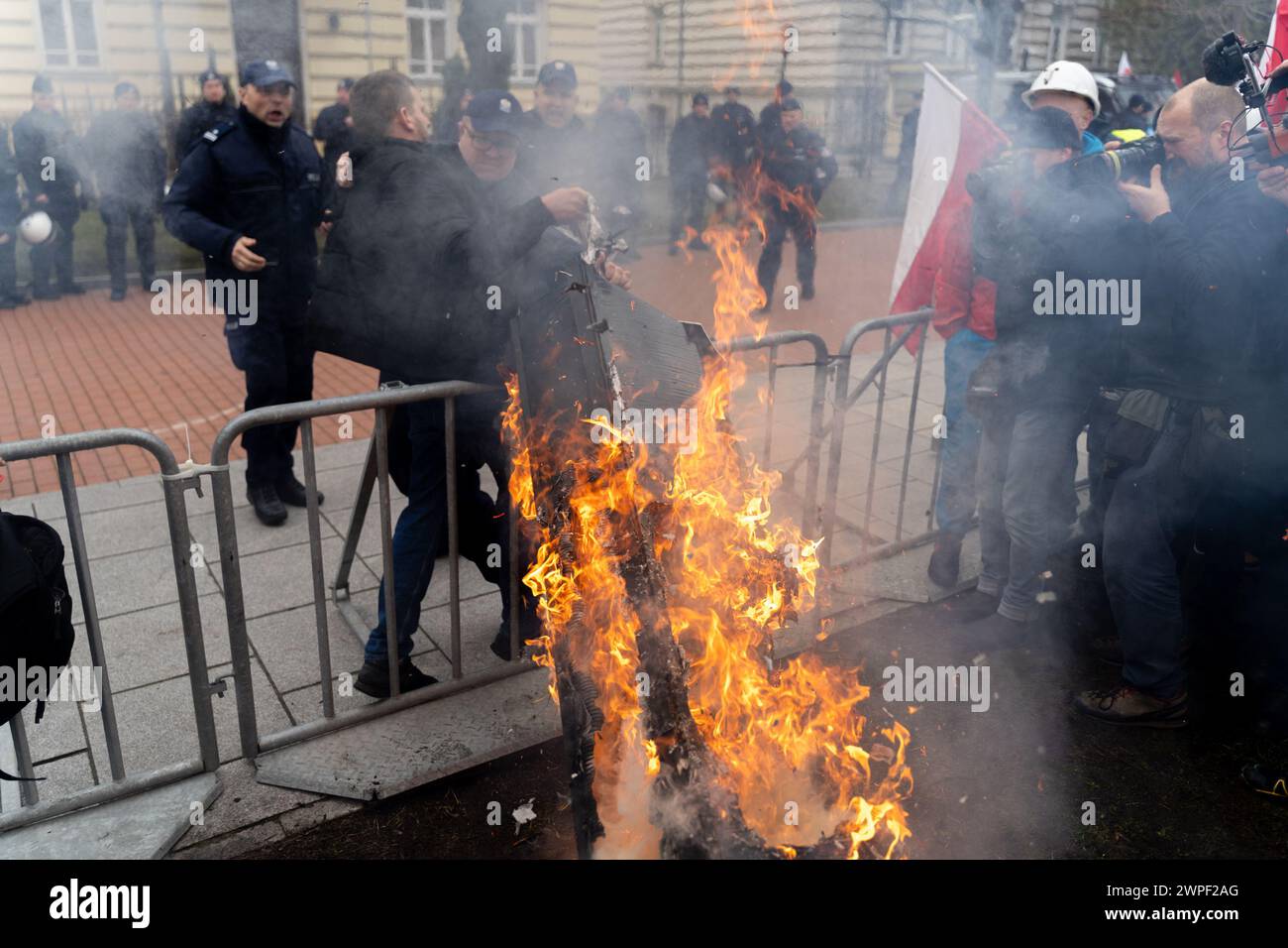 Un manifestant tient un cercueil en feu (symbolisant la mort d'un fermier polonais) alors qu'il tente de le déplacer dans les locaux de la Chancellerie du premier ministre lors d'une manifestation. Une semaine après la manifestation précédente, des dizaines de milliers d'agriculteurs polonais se sont rassemblés devant le bureau du premier ministre et ont ensuite défilé devant le parlement polonais pour exprimer leur opposition à la politique agricole de l'Union européenne. En particulier, ils se sont opposés à la récente prorogation par la Commission européenne du commerce hors taxes avec l'Ukraine jusqu'en 2025, se sont opposés à l'adoption du Green Deal de l'UE et ont protesté contre le Banque D'Images