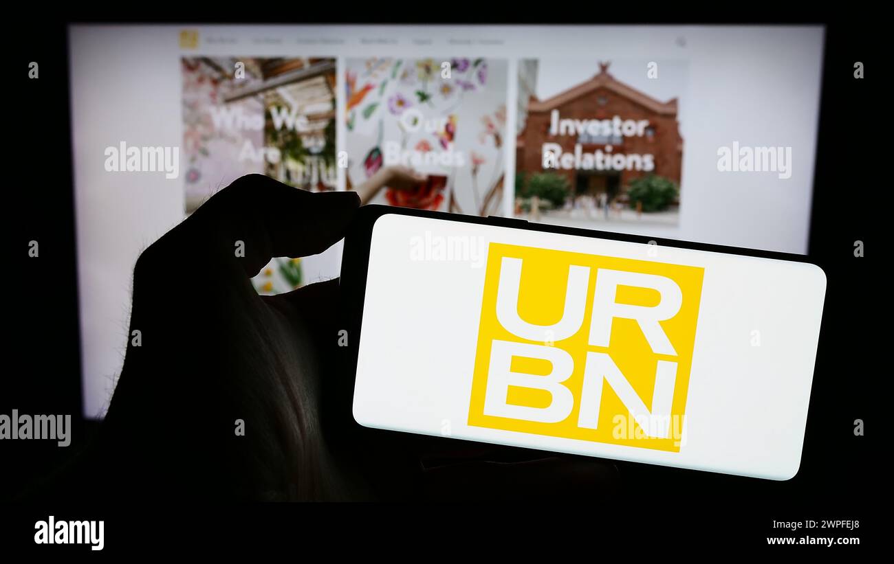 Personne tenant un smartphone avec le logo de la société américaine de mode rapide Urban Outfitters Inc (URBN) devant le site Web. Concentrez-vous sur l'affichage du téléphone. Banque D'Images