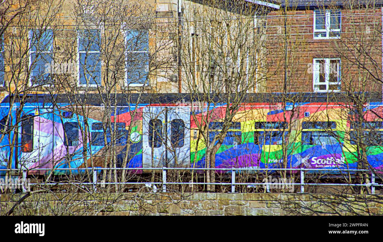 Glasgow, Écosse, Royaume-Uni. 7 mars 2024 : Météo britannique : ensoleillé dans la ville vu les habitants et les touristes dans les rues du centre-ville. Train écossais peint de couleurs vives Pride of ScotRail train. Avec la peinture de la communauté LGBTQ+ drapeau de progrès. avec bacjkground de tenements. Crédit Gerard Ferry/Alamy Live News Banque D'Images