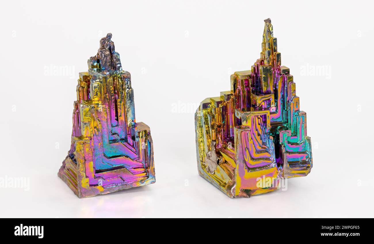 Beaux cristaux de trémie de bismuth cassants colorés avec structure en escalier sur fond blanc. Deux pièces en métal lourd d'élément chimique diamagnétique. Banque D'Images