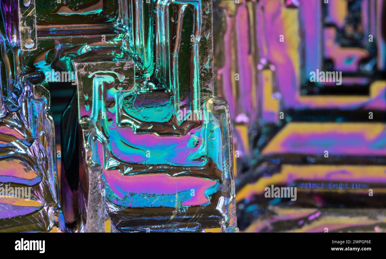 Gros plan d'un cristal de trémie à partir d'un élément chimique de bismuth dans un fond irisé coloré. Beau détail de texture de métal lourd diamagnétique cassant. Banque D'Images