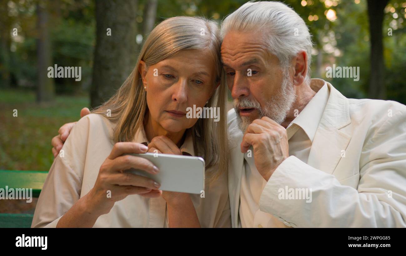 Confus inquiet Caucasien vieux couple aîné de famille retraité homme âgé femme à la recherche d'un smartphone recevant de mauvaises nouvelles notification réaction négative Banque D'Images
