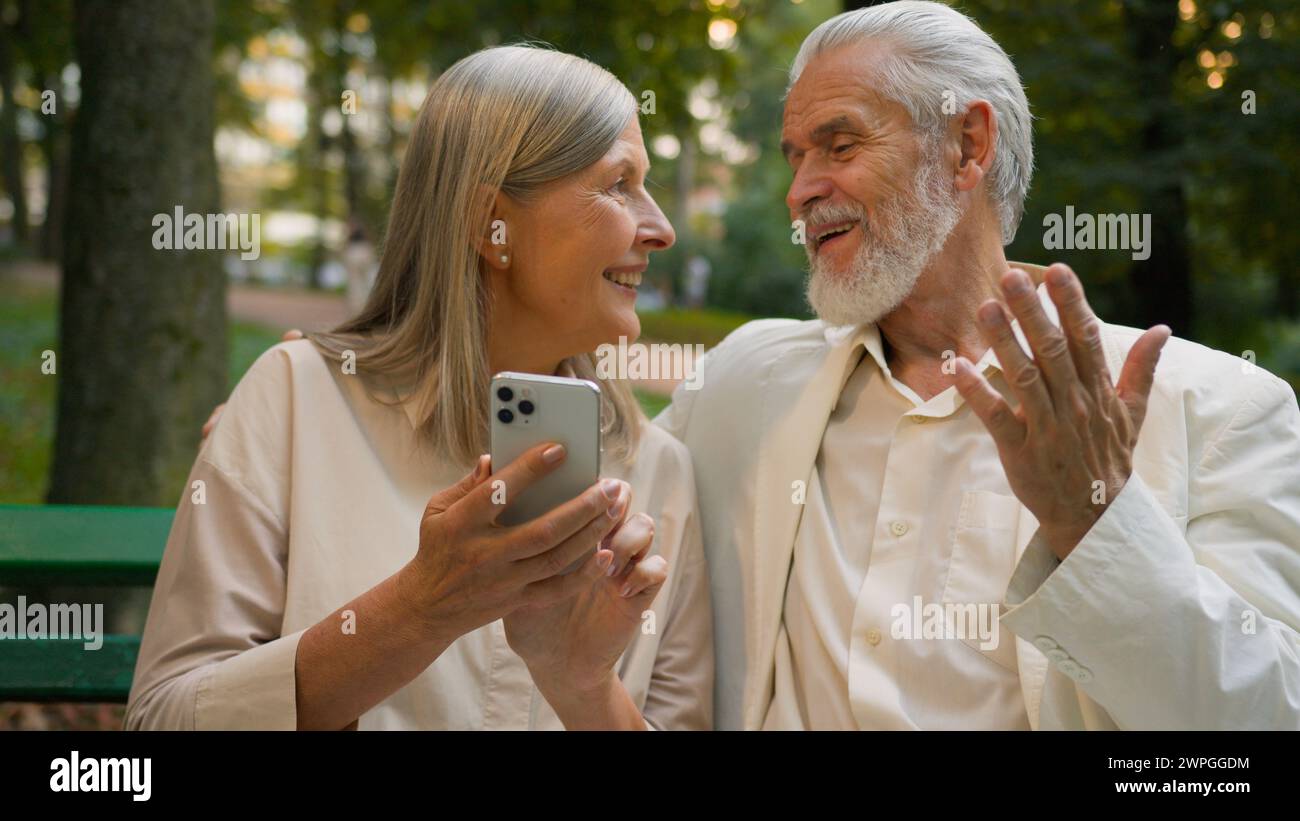 Heureux couple âgé caucasien retraité famille des années 70 marié des conjoints âgés s'amusant en utilisant l'application d'appel en ligne de téléphone mobile en plein air parc naturel de la ville Banque D'Images