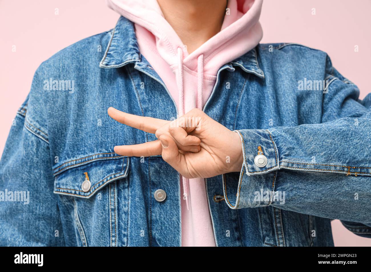 Jeune homme sourd muet utilisant la langue des signes sur fond rose, gros plan Banque D'Images