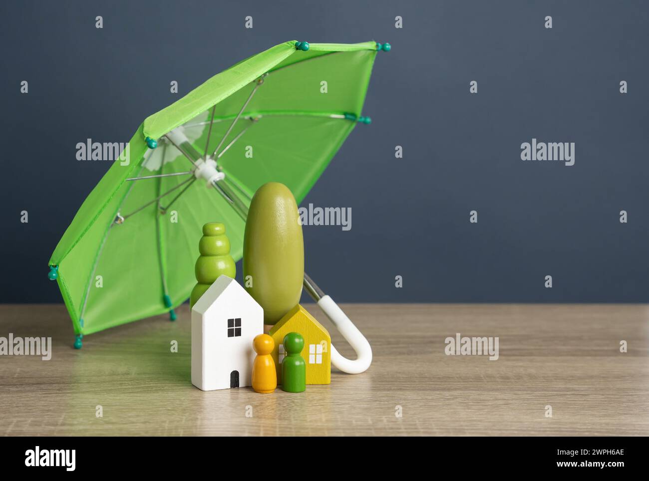 Maison avec des gens sous un parapluie. Assurance de biens. Sécurité financière. Réparations ou reconstruction en cas de sinistre couvert. Protégez vos investissements Banque D'Images