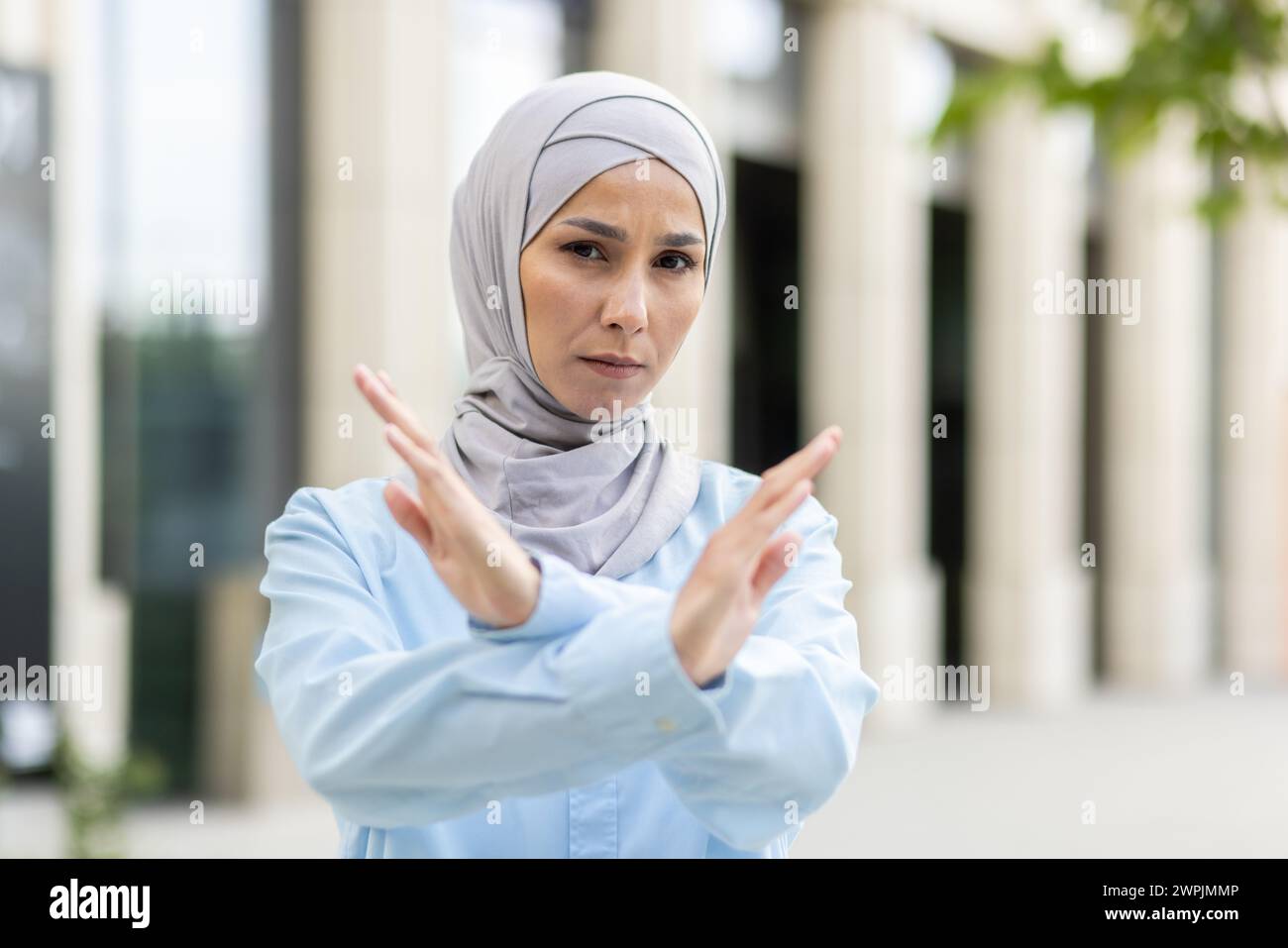 Une femme musulmane adulte habilitée portant un hijab croise les bras dans un geste en « X », signalant l'arrêt ou le déni à l'extérieur. Banque D'Images