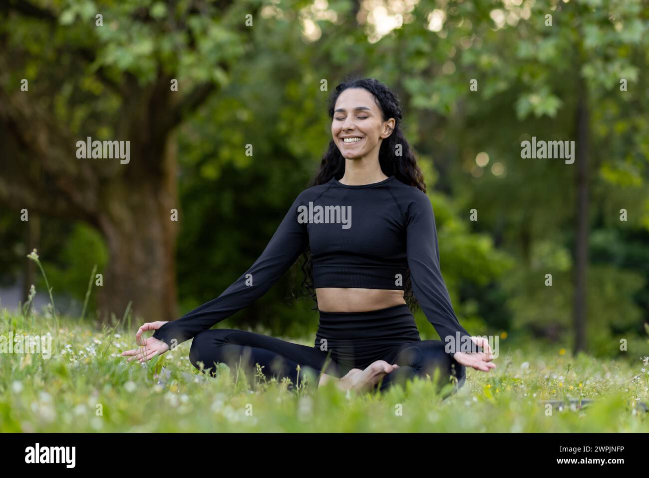Contenu la jeune femme en vêtements d'activité aime la méditation de yoga dans un parc paisible, incarnant le bien-être et la pleine conscience. Banque D'Images
