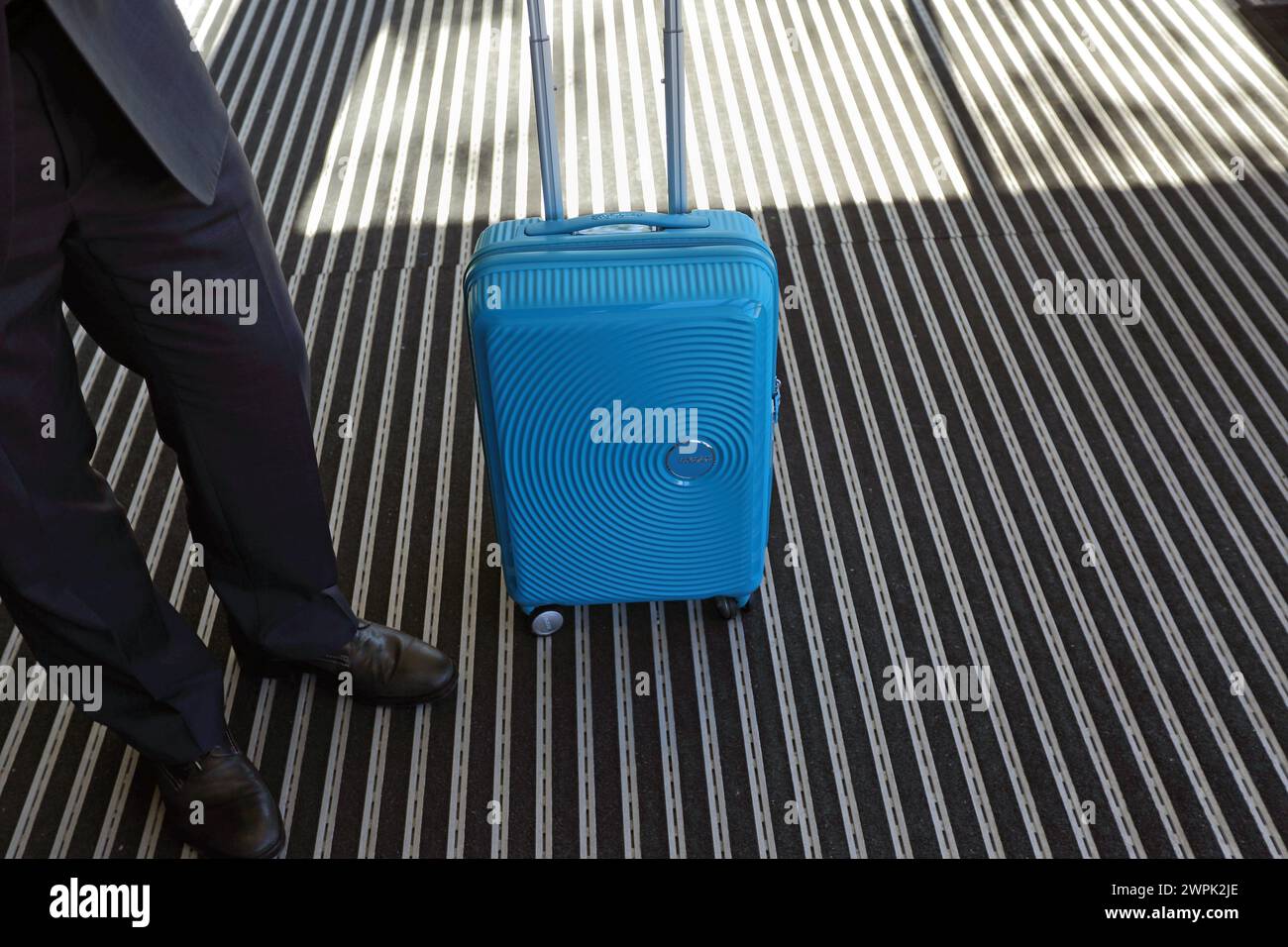 Voyageur d'affaires en costume d'attente avec valise à roulettes. Homme d'affaires attendant un taxi Uber pour l'aéroport. Banque D'Images