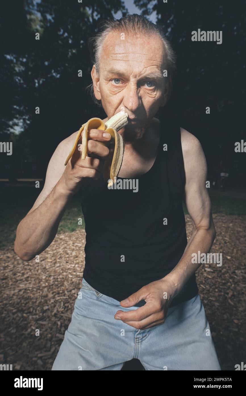 Homme laid de mauvaise condition mangeant des bananes fraîches après l'entraînement Banque D'Images