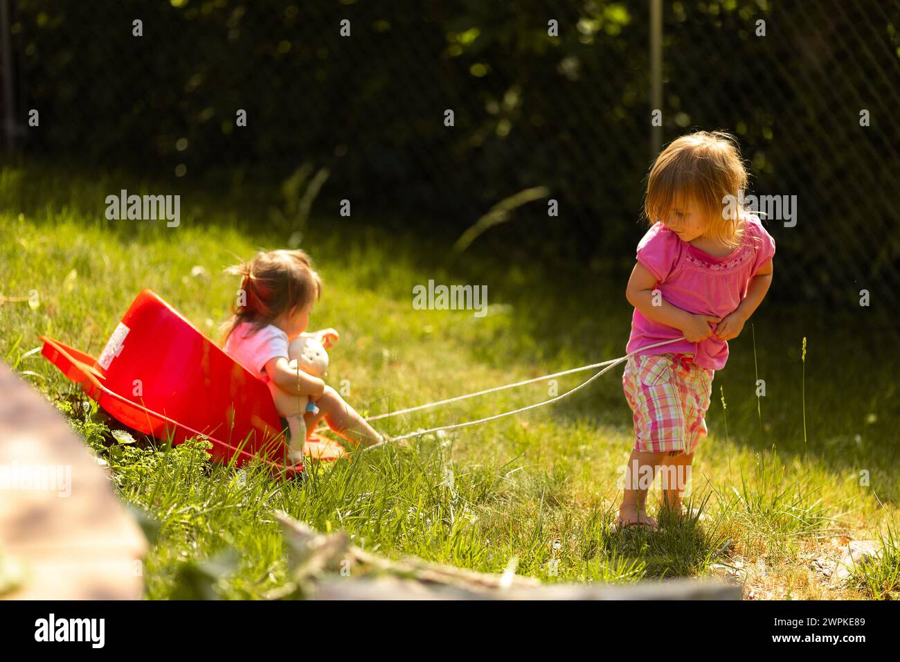 La petite fille tire joyeusement sa sœur sur un traîneau Banque D'Images