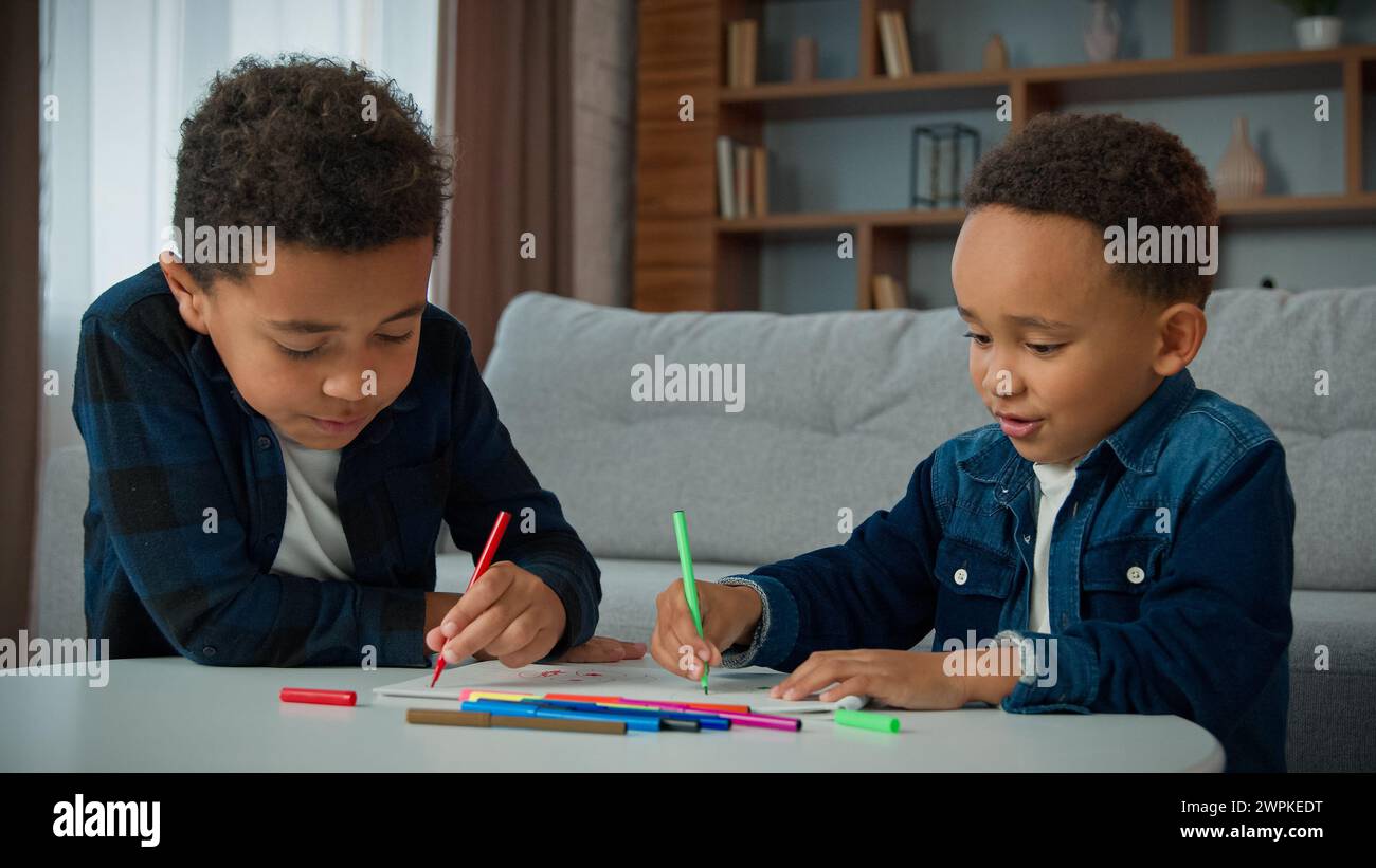 Deux garçons afro-américains ethniques enfants profiter de l'art de passe-temps à la maison devoirs dessiner écoliers frères élèves frères frères enfants enfants dessin avec des marqueurs colorés Banque D'Images