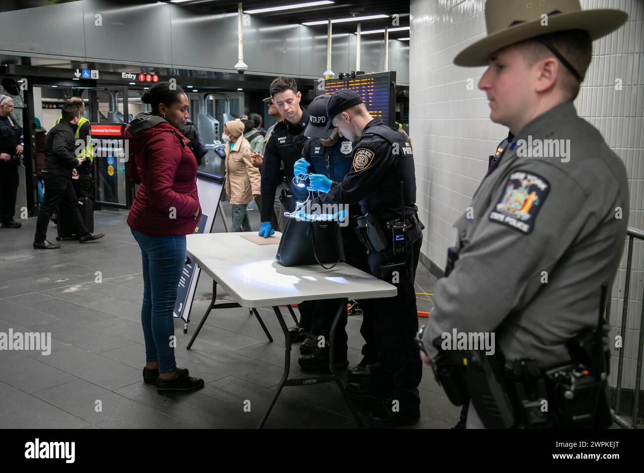 New York, États-Unis. 7 mars 2024. Des policiers de la Metropolitan Transportation Authority (MTA) fouillent le sac d'un passager à un poste de contrôle de sécurité à Penn Station à New York, aux États-Unis, le 7 mars 2024. L'État de New York prend de multiples mesures pour faire face aux crimes dans le métro de la ville de New York, y compris le déploiement de centaines de membres de la Garde nationale. Crédit : Michael Nagle/Xinhua/Alamy Live News Banque D'Images