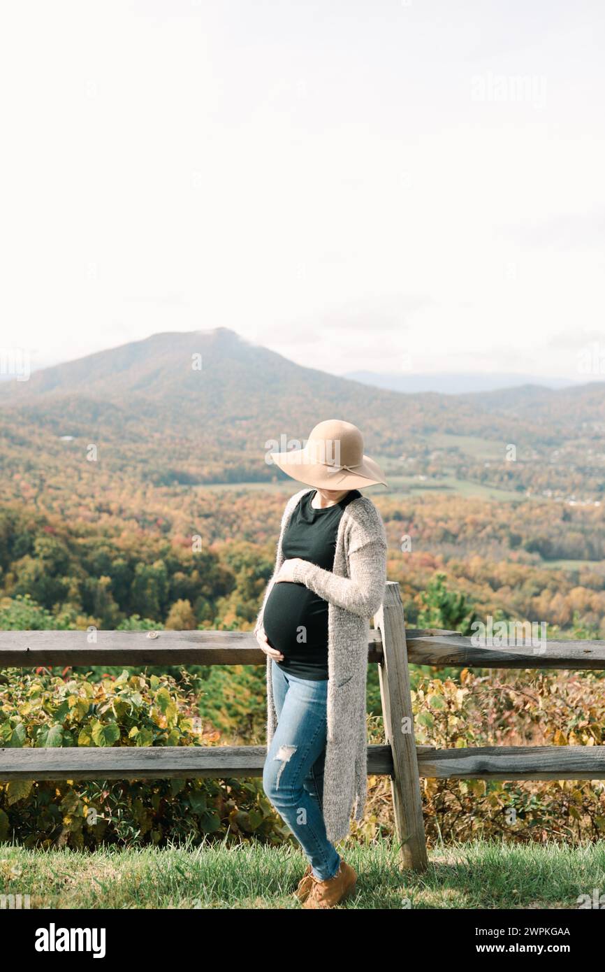 Future mère à côté de la clôture surplombant le paysage de montagne Banque D'Images