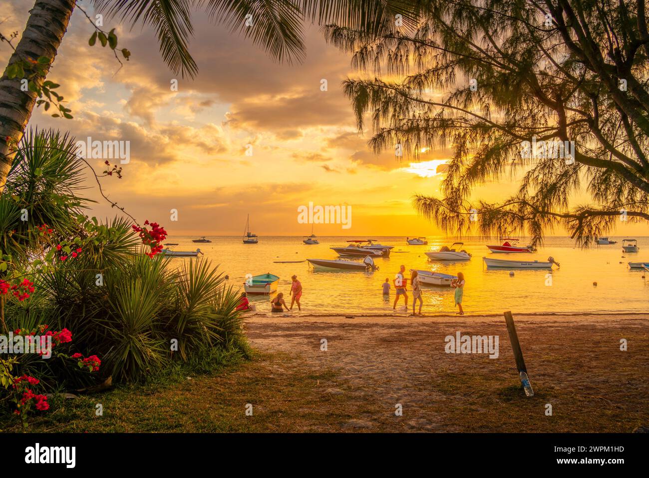 Vue des bateaux et des gens sur la plage publique de mon Choisy au coucher du soleil, Maurice, Océan Indien, Afrique Banque D'Images