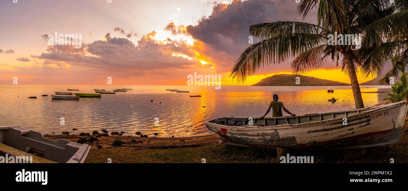 Vue de l'homme local assis sur le bateau regardant le Morne depuis le Morne Brabant au coucher du soleil, Savanne District, Maurice, Océan Indien, Afrique Banque D'Images