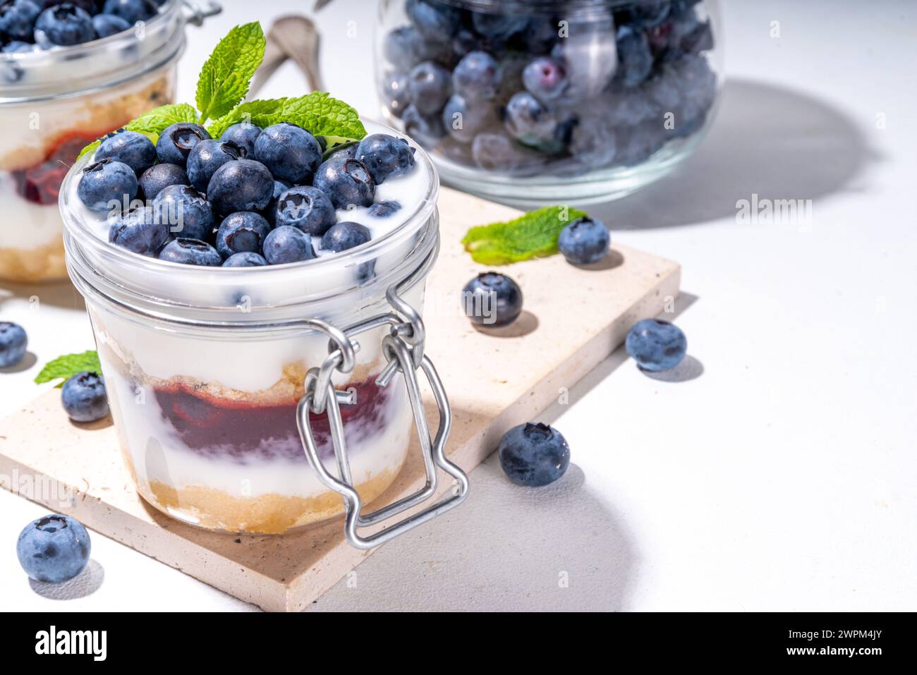 Dessert superposé aux myrtilles, gâteau au fromage en verre avec biscuit à la vanille, yaourt crémeux, garniture à la confiture et myrtille fraîche Banque D'Images