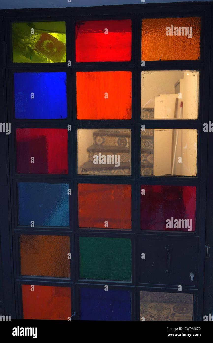 Un escalier couvert carrelé derrière une porte en verre coloré Banque D'Images