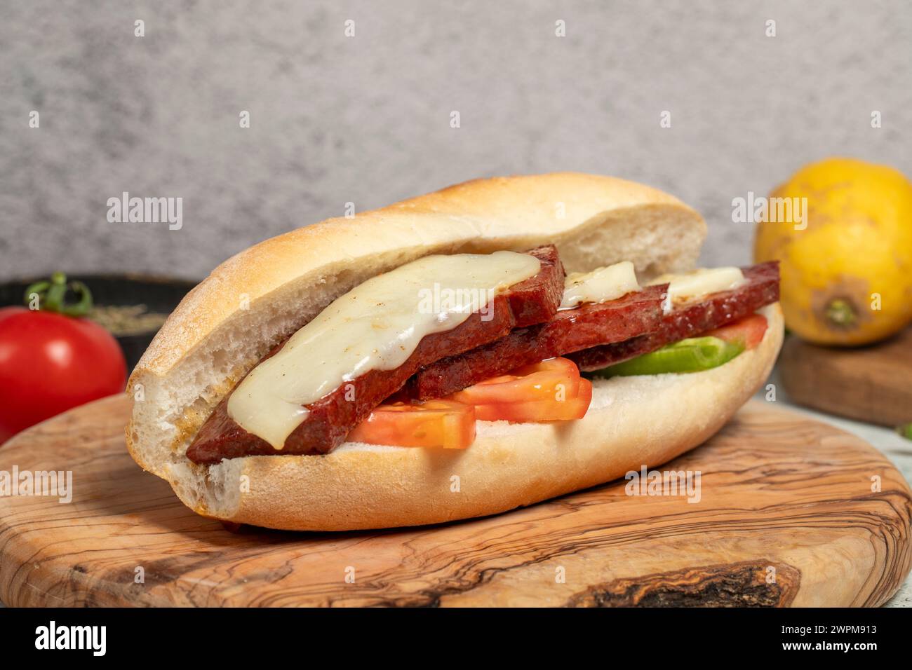 Sandwich au pain turc avec saucisse kashar sur le tableau de présentation. Saucisse dans du pain préparé avec des tomates, des poivrons et des boulettes de viande. Nom local ekmek Banque D'Images