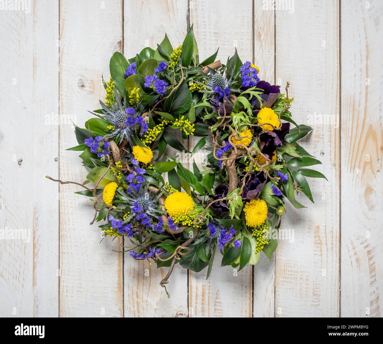 Couronne de printemps de fleurs violettes et jaunes sur un fond rustique en bois blanchi à la chaux Banque D'Images