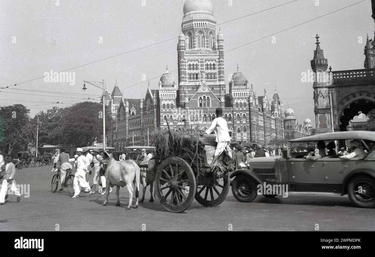 Années 1930, historique, scène de rue dans la vieille ville de Karachi, où l'ancienne forme de transport, un boeuf & chariot, partage une route avec la nouvelle, une automobile. Un grand bâtiment avec dôme vu sur la photo montre la culture islamique de la ville, qui a été introduite au VIIIe siècle. À cette époque, elle faisait partie de l'Empire indien britannique, avec la région divisée en provinces séparées, le Sind, le Pendjab et l'Agence du Baloutchistan. En 1947 avec l'indépendance, il est devenu une partie du Pakistan. Banque D'Images