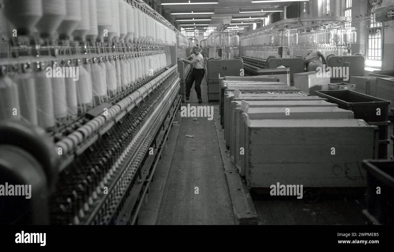 Années 1950, historique, un opérateur masculin travaillant dans une grande salle de filage de mule dans une usine de coton, USA. Banque D'Images