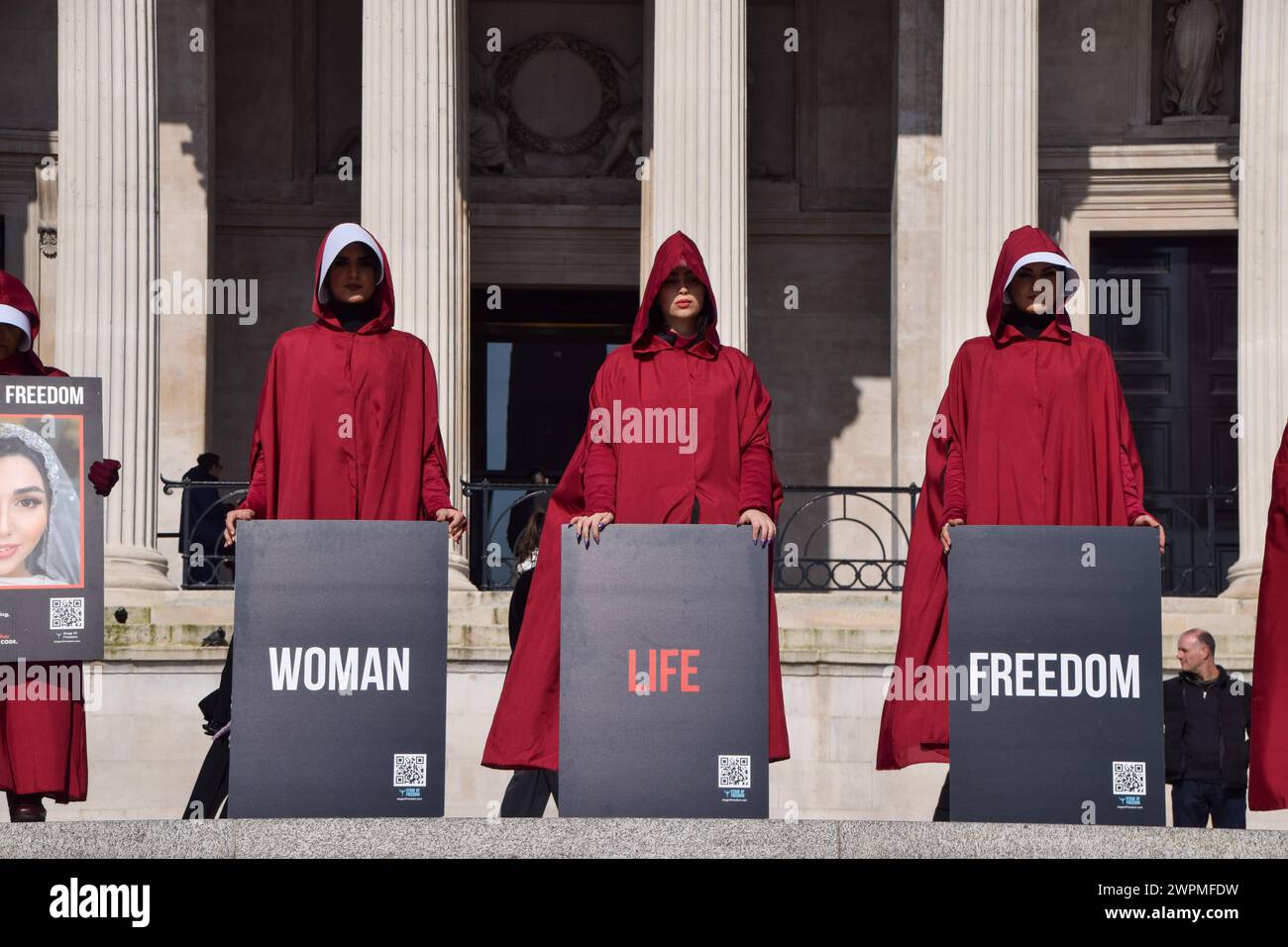 Londres, Royaume-Uni. 8 mars 2024. Les manifestants se tiennent debout sur Trafalgar Square avec des pancartes « Woman Life Freedom ». Les femmes portant les costumes de Handmaid's Tale défilent dans le centre de Londres pour soutenir la liberté de l'Iran lors de la Journée internationale de la femme. Crédit : Vuk Valcic/Alamy Live News Banque D'Images