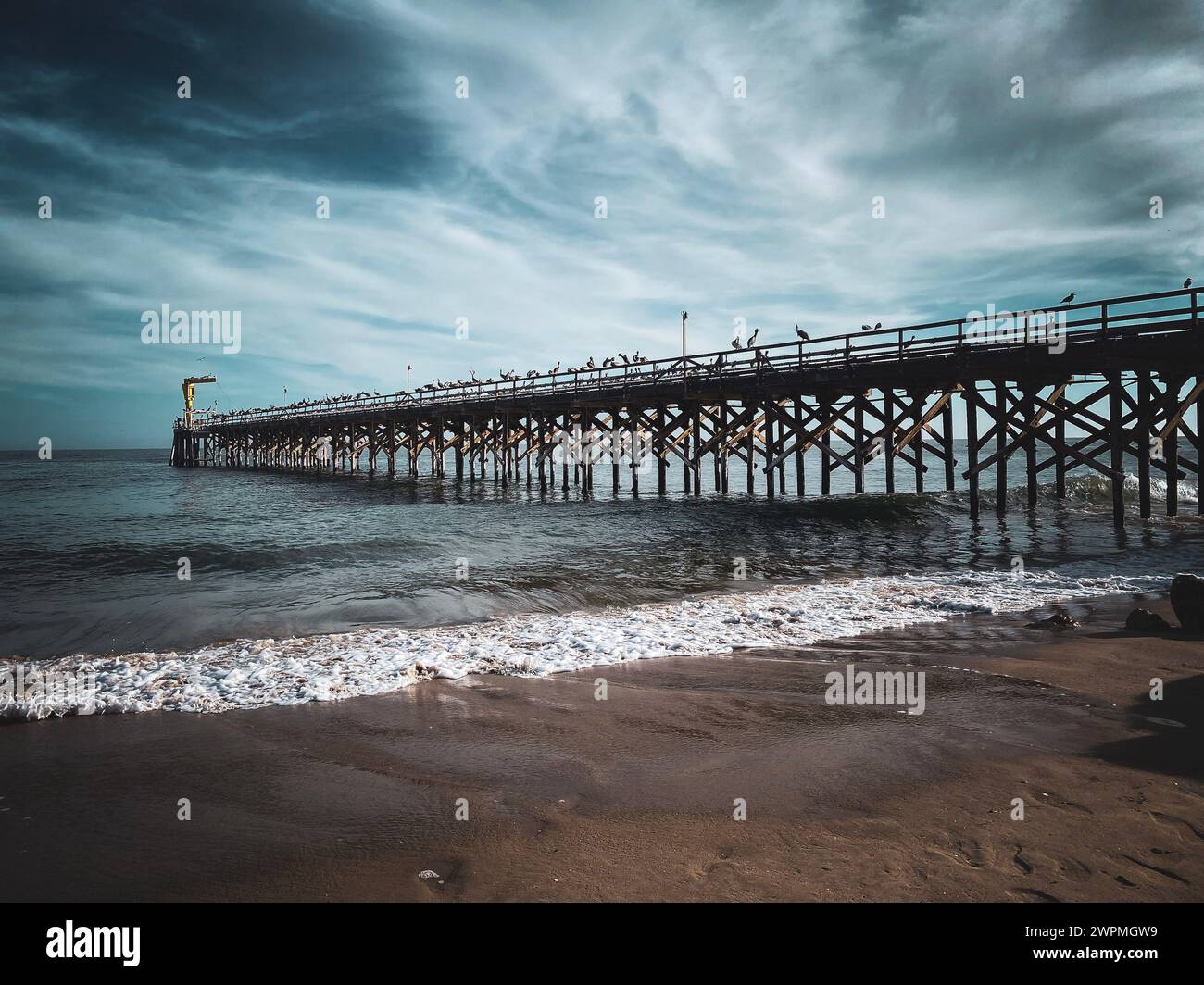 Une jetée sous un ciel nuageux sur une plage de sable Banque D'Images